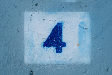 Number four with blurred edges drawn on a blue wall in a white rectangle