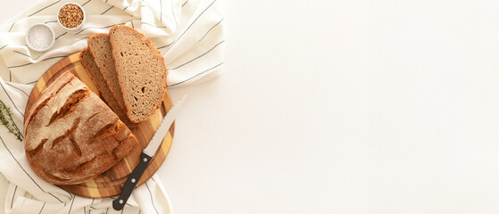 Canvas Print - Wooden board with sliced loaf of bread, wheat grains, thyme and knife on white background