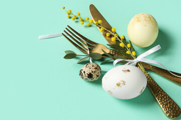 Wall Mural - Cutlery for table setting with Easter eggs and mimosa flowers on turquoise background