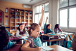 © Marko Geber - Young Caucasian girl raising her hand for the teacher while at the elementary school classroom
