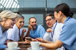 © Marko Geber - Group of diverse doctors laughing on coffee break outdoors