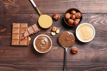 Canvas Print - Spoons and bowls of sweet chocolate spread and nut butter on wooden background