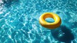 © bestimagestock - A vibrant yellow ring floats gracefully on the surface of a tranquil pool of clear blue water.