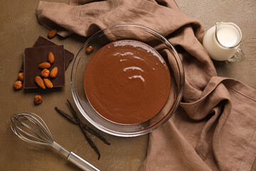 Canvas Print - Bowl with hot chocolate, napkin and whisk on brown background. Top view