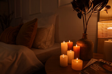 Canvas Print - Burning candles and vase with dried flowers on table in bedroom at night