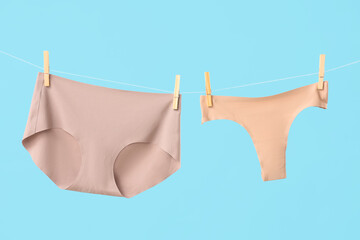 Wall Mural - Female panties hanging on clothesline against blue background