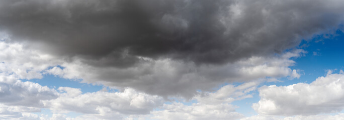 Wall Mural - Panorama of a summer cloud filled sky fills the panorama with patches of blue,
