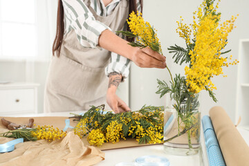 Canvas Print - Female florist making bouquet with mimosa flowers at table in room