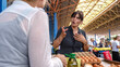 © HI Pictures - An elderly retired blonde woman happily shopping at a fruit and vegetable bazaar on a summer day