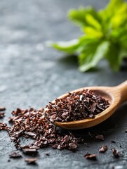 Poster - Wooden spoon filled with finely grated chocolate resting on a textured black stone surface with fresh mint leaves : Generative AI