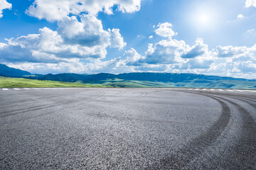 Wall Mural - Asphalt road and green mountain under a cloudy blue sky