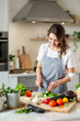 © Javier - Happy woman preparing food in a stylish kitchen.