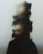© Mariarti - An abstract portrait of a figure in dark clothing against a pale background. The figure's features are blurred and distorted by a dark, vertically oriented smudge effect.