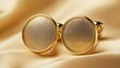 © Artittaya - A pair of golden cufflinks with engraved details, arranged stylishly on a smooth gold background