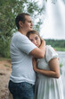 © Maryna - Romantic couple kissing and embracing near a lake and forest on a cloudy day.