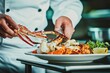 © whitestorm - Professional chef carefully arranges crab legs on a seafood platter with grilled shrimp, garnished with lemon, showcasing culinary expertise and high-end cuisine.