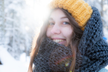 Happy smiling young woman in scarf and hat enjoying winter weather in snowy winter park