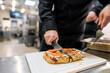 © pavel siamionov - A chef skillfully slices a freshly baked pizza on a cutting board in a commercial kitchen, showcasing delicious toppings and a crispy crust.