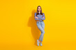 © deagreez - Trendy young woman standing against a vivid yellow background, wearing a stylish patterned shirt and denim, exuding charm and happiness