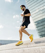 © muse studio - Young man jogging down steps in an urban area during a sunny day