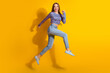 © deagreez - Cheerful young woman in casual jeans and colorful top jumping against yellow background with enthusiasm