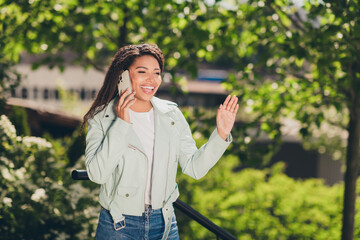 Wall Mural - Smiling young woman in urban setting enjoying a phone call on a sunny day outdoors