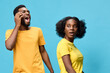 © SHOTPRIME STUDIO - Excited diverse couple with bright yellow outfits expressing joy against a vibrant blue background, showcasing happiness and connection in a modern style