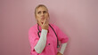 © Krakenimages.com - Woman thinking in pink scrubs with stethoscope against isolated pink background.