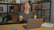 © Krakenimages.com - Woman celebrating success at desk with laptop in modern office surrounded by food jars and shelves, expressing excitement and achievement indoors.