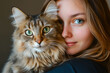 © MVProductions - Portrait of young woman holding cute siberian cat with green eyes. Female hugging her cute long hair kitty. Background, copy space, close up. Adorable domestic pet concept