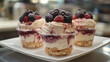 © samuel_miles - Delicious layered dessert with berries served in cups on a white plate at a cafe