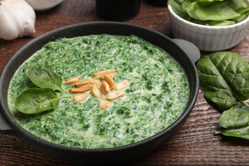 Sticker - Delicious spinach sauce with peanuts served on wooden table, closeup