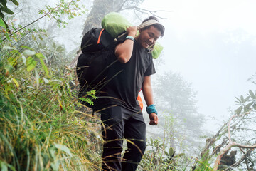 Wall Mural - portrait of strong sherpa man working as porter carrying huge cargo with traditional method on foreh