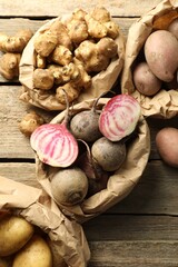 Wall Mural - Different raw root vegetables in paper bags on wooden table, flat lay