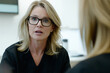 © Enigma - Doctor wearing glasses and black scrubs is speaking seriously to a patient in a medical office, providing important information and guidance