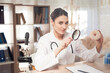 © Oleh Veres - Female doctor sitting at desk in office with microscope and stethoscope. Woman is looking at donut with magnifyer.