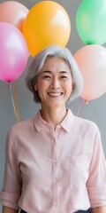 Wall Mural - A woman is smiling and holding balloons in her hand. The balloons are of different colors, including pink, yellow, and orange. Concept of joy and celebration, as the woman is happy