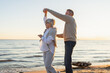 © Юлия Завалишина - Keep moving. Romantic senior mature couple dancing together on beach outdoor recreation. Happy smiling family retired man woman husband wife having fun enjoying time together. Family moment love care