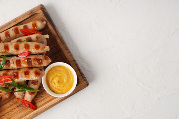 Poster - Wooden board with tasty grilled sausages, chili pepper and bowl of mustard on white background