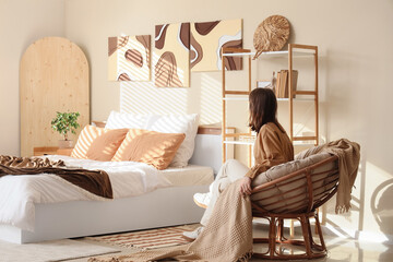 Poster - Beautiful young woman sitting in armchair in bedroom