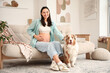 © Pixel-Shot - Young happy pregnant woman with cute Australian Shepherd dog sitting on sofa at home