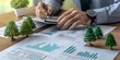 © AminaDesign - A savvy businessman meticulously analyzes ESG data represented through green financial charts and cute toy trees, while concentrating on implementing sustainable and responsible business practices
