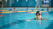 © Postmodern Studio - Asian young female swimmer practicing in indoor pool with goggles and cap