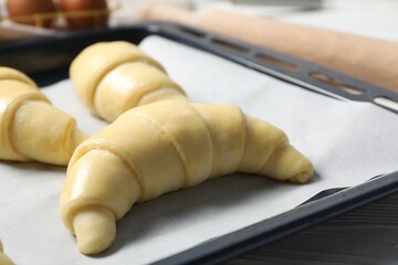 Wall Mural - Fresh raw croissants on wooden table, closeup