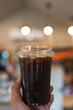© Dontree - Closeup shot of man holding a plastic glass of iced black coffee or americano
