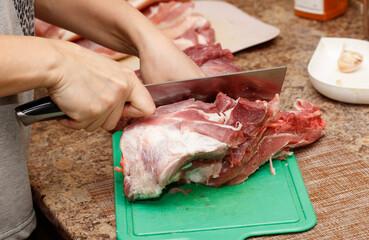 Wall Mural - A person is cutting meat on a cutting board