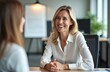 © miss irine - Happy blonde hr manager smiles at job applicant during interview at workplace. Executive women discuss project in corporate office, recruiting employee or business consultation.