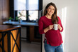 © NDABCREATIVITY - Pregnant woman practicing relaxation with a warm cup of tea, embracing self-care and wellness.