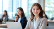 © Tondone - young woman smiles confidently while working on laptop in modern office. bright environment and professional attire create positive atmosphere for productivity