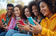 © miss irine - Multiracial young people use mobile phones outdoors, sharing media content fun. Group of diverse friends, students, teenagers connected in city, watching video together. Trendy cellular smart devices